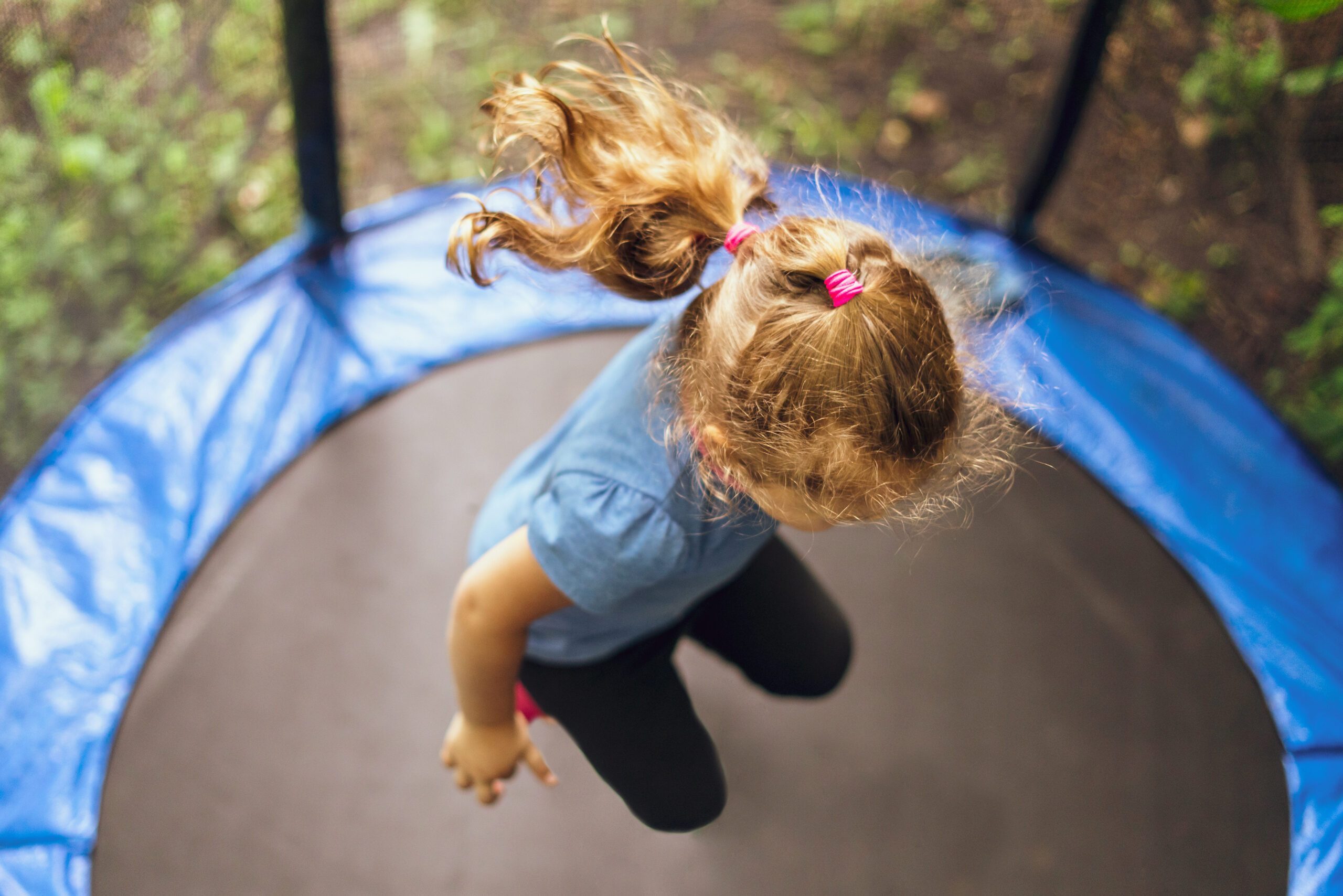 Little girl jumping on a trampoline on a summer day.